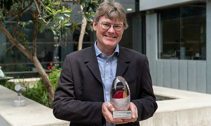 David Komander standing outside with his award trophy